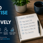 Business owner prioritising tasks using a notebook, laptop and organised workspace to improve productivity.